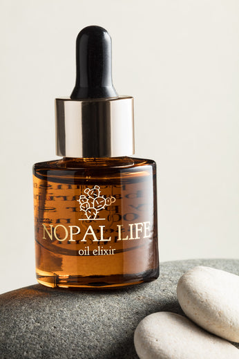 Huile élixir Nopal Life – flacon en verre ambré avec pipette dorée, posé sur galets naturels
